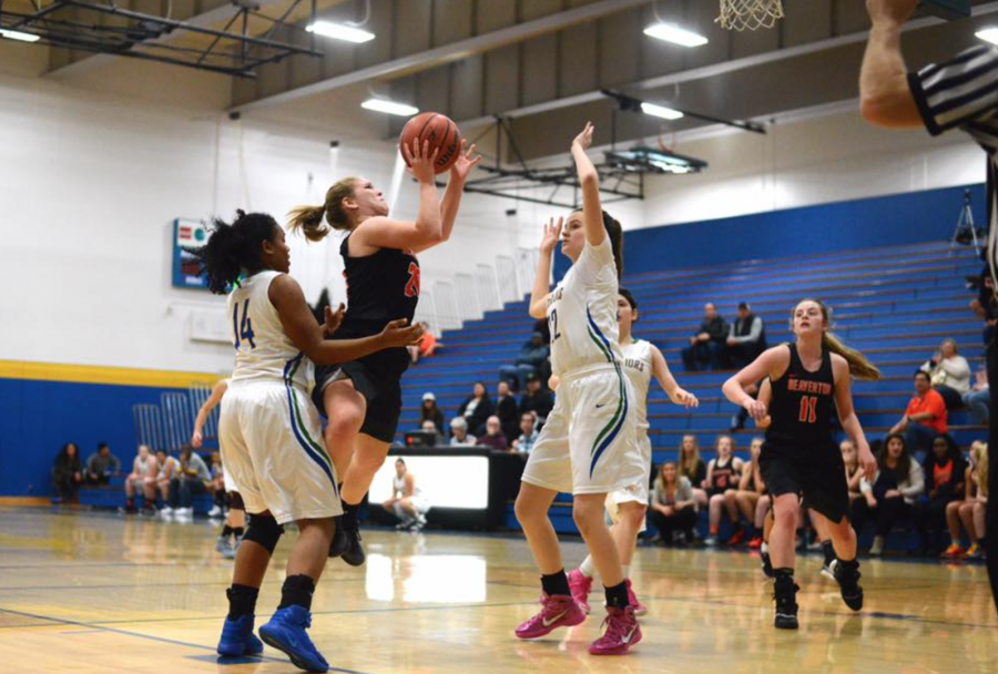 Senior Maddie McKenna goes for a jump shot as two Aloha players defend her.
