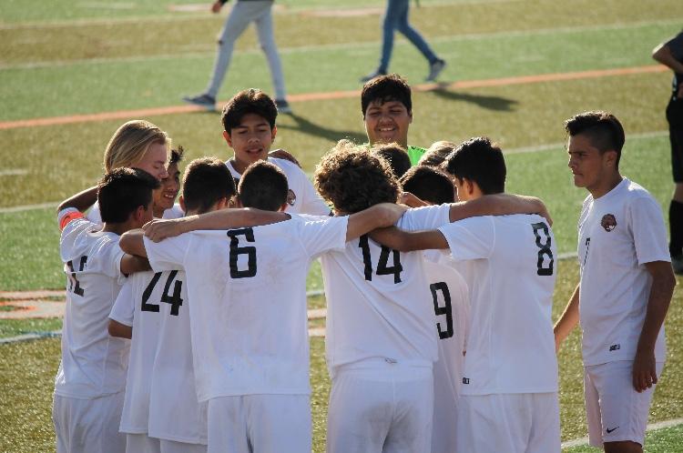 The JV boys soccer team huddle as they strategize during halftime.