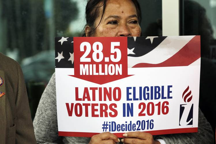 A Latinx person holds a sign, encouraging Latinos to vote.