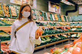 A woman debates which produce to buy at a grocery store.