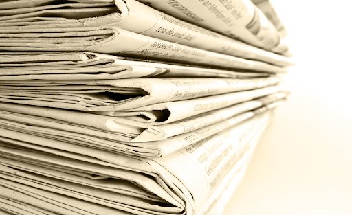 A ray of light shines upon a stack of newspapers.