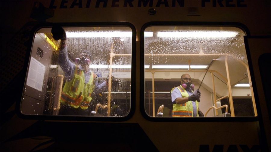 Two TriMet employees sanitize a vehicle at night.