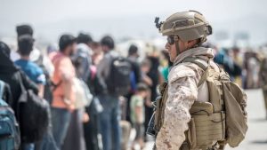 Afghan refugees head toward an evacuation point as a US Marine looks on